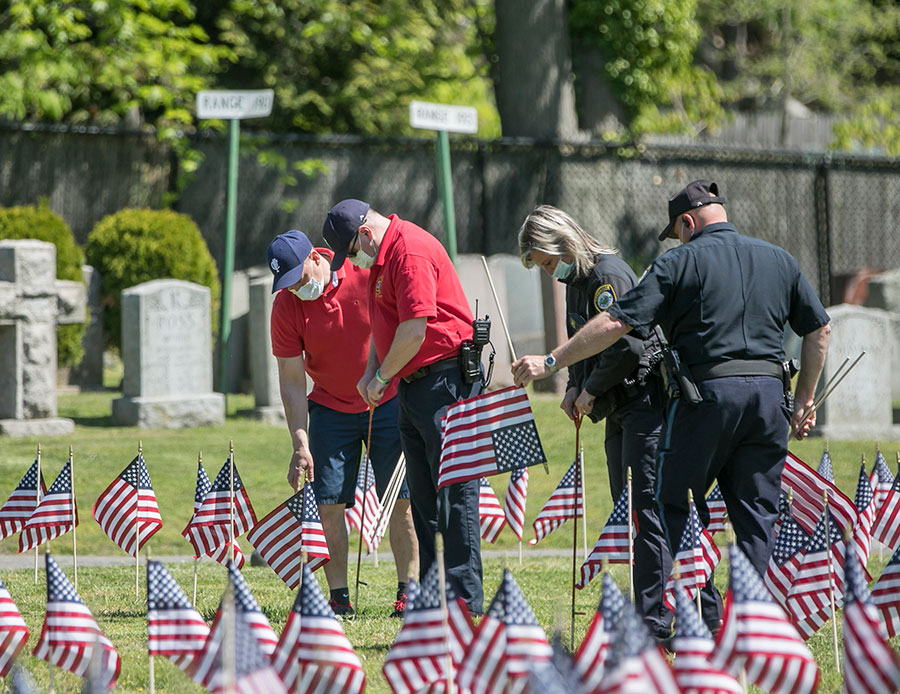 Members of the Cambridge Fire and Police Departments place flags at the graves of Cambridge's fallen heroes